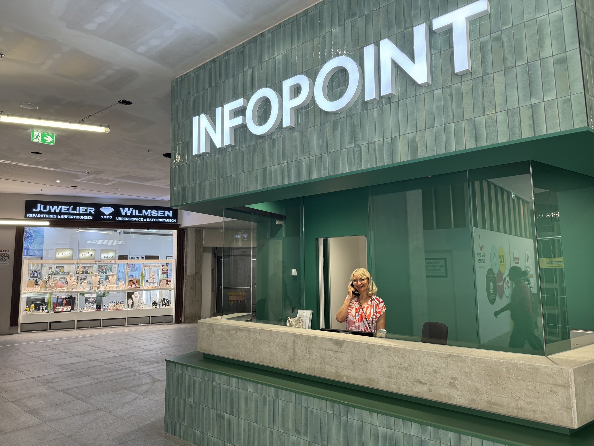 neuer Infopoint in grün mit Frau die telefoniert
